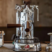 La Pavoni Professional Lusso coffee machine in polished chrome finish with wooden handles, featuring a pressure gauge, steam wand, and lever-operated brewing system, displayed on wooden countertop with classic Italian espresso maker design